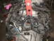 1964 Ford Ranchero - Engine assembly with numerous hoses and wiring harnesses, suspended by chains and a red lifting bracket.