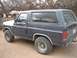 1982 Ford Bronco - A dark blue and white Ford Bronco is parked outdoors, viewed from its side profile.