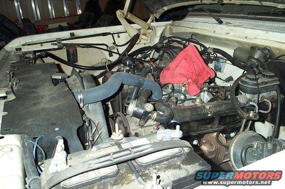 Engine bay with a red rag draped over the engine block. Battery is visible in the foreground