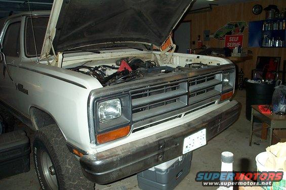 White pickup truck with hood open, showing engine bay. Parked in a garage