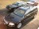 2002 Volkswagen Passat - Three cars parked outside, including a black 2002 Volkswagen Passat wagon with a car bra.