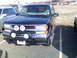 1998 Chevrolet Tahoe - Front view of a black Chevrolet Tahoe, equipped with a bull bar and auxiliary lights. Another vehicle is parked to the left.