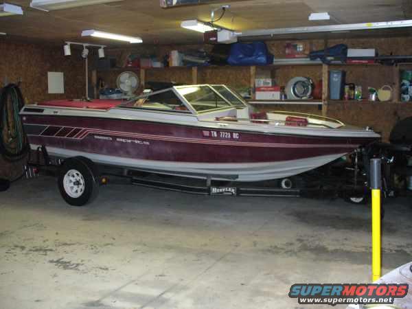 Boat on a trailer in a garage. It has a red stripe and the text 'SEA SPORTS' on the side