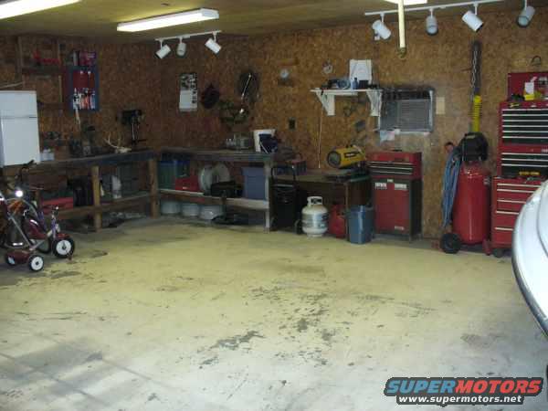 Garage interior with workbench, tool chests, air compressor, and a small red cart