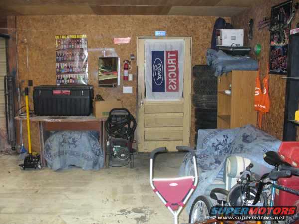 Garage interior with a large black toolbox on a table, a pressure washer, and a covered object