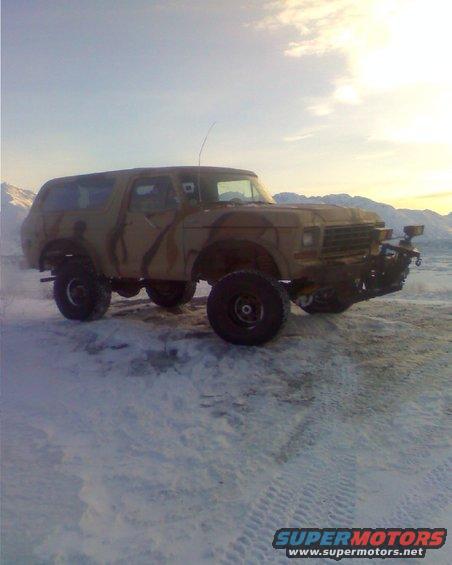 Camouflaged Ford Bronco with aftermarket bumper in a snowy landscape