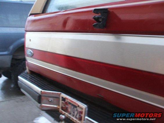 Red and silver 1991 Ford Bronco rear with dented tailgate, chrome bumper, and license plate