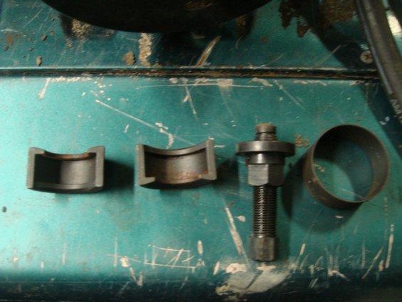 Metal bearing separator tool with threaded rod and nuts, and two U-shaped pieces, on a teal workbench