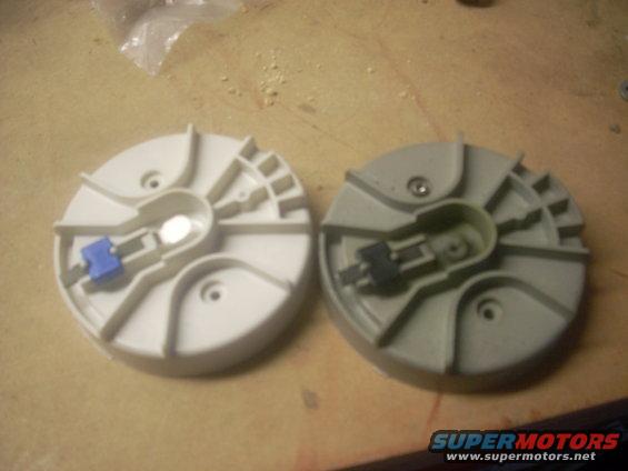 Two automotive distributor caps on a wooden surface