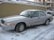 2004 Ford Crown Victoria - A silver 2004 Ford Crown Victoria sedan is parked in the snow, showing its front three-quarter view.