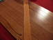 1988 Ford Bronco - A close-up view of wood flooring with a single plank laid across it, next to a red carpeted area.