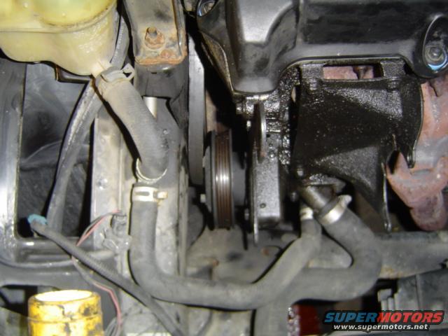 engine bay with hoses, belts, and pulleys visible