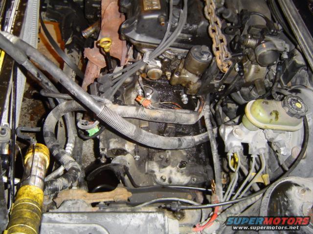 Engine bay with engine hoist chain attached to the engine. Brake fluid reservoir visible