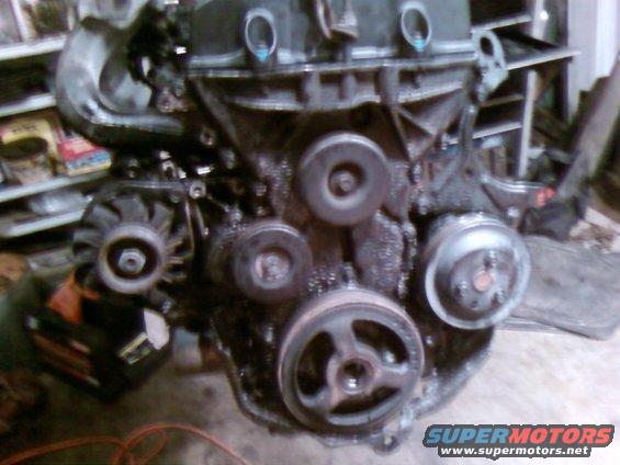 Engine with pulleys and alternator, covered in oil and grime