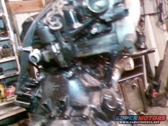 Engine assembly with hoses and belts, suspended by a chain