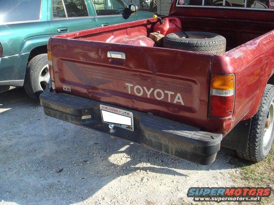 Red 1991 Toyota pickup truck rear with V6 badge and "TOYOTA" tailgate lettering