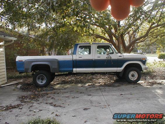 Side view of a white and blue Ford F-Series Crew Cab pickup truck, lifted with large tires