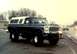 1979 Ford Bronco - This lifted pickup truck, possibly a 1979 Ford F-Series, features a white camper shell and off-road tires.