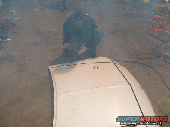 White hood with red emblem being welded by a person in protective gear