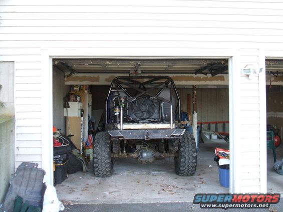 Modified off-road vehicle with roll cage and large tires in a garage