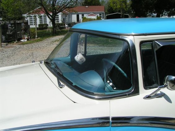 White and blue 1956 Ford Fairlane with fuzzy dice hanging from the rearview mirror