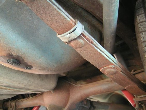 Undercarriage view of a rusty leaf spring and differential with a tire visible