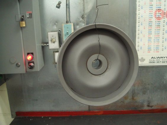 Grinding wheel hanging by wire, next to control panel with red light and timer