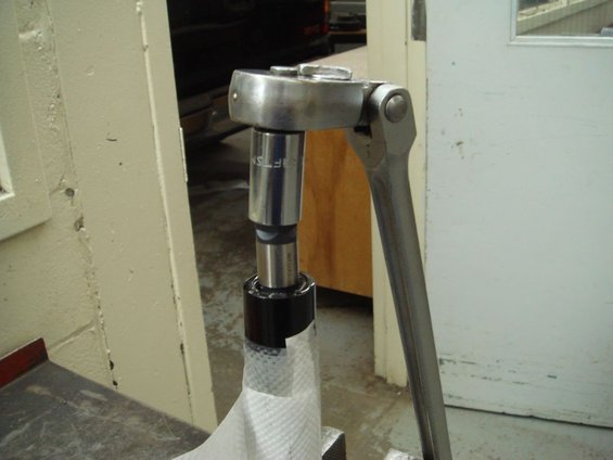 Drag link with a socket wrench attached, partially wrapped in white paper towel