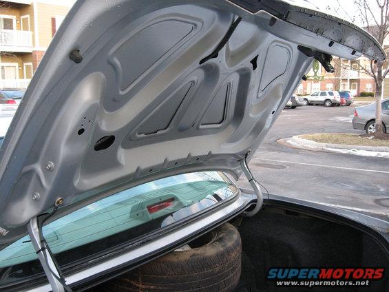 Car trunk open, showing spare tire and interior. Supermotors.net logo visible