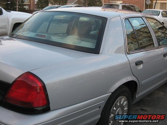 Silver sedan's rear quarter panel and taillight, with a white pickup truck to the left