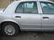 2004 Ford Crown Victoria - This silver 2004 Ford Crown Victoria is shown from the side, highlighting its rear door and wheel assembly.