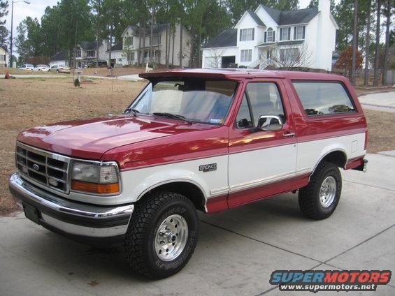 Red and white Ford Bronco parked on a driveway, front 3/4 view