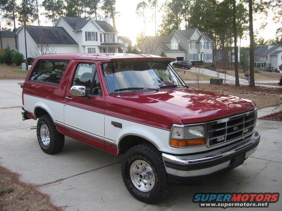 Red and white Ford Bronco parked on a driveway, front 3/4 view