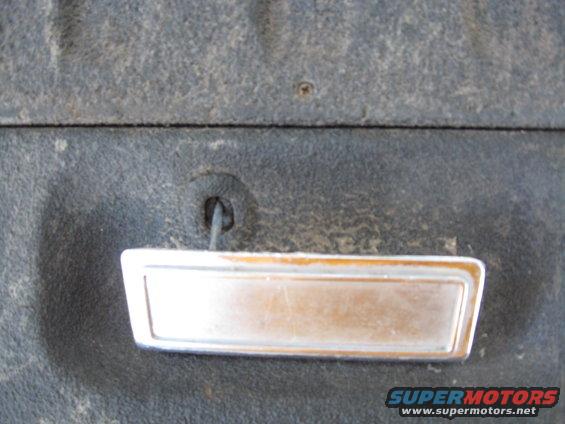 Interior door handle with chrome trim on a dark textured surface