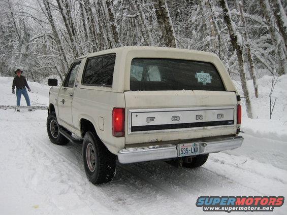 1980 Ford Bronco parked on snowy road, person standing nearby