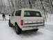 1980 Ford Bronco - White 1980 Ford Bronco in a snowy forest setting with a person in the background.