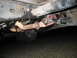 1980 Ford Bronco - The undercarriage of a vehicle, rusted exhaust pipes and suspension parts, with a tire visible below.