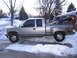 1998 GMC Sierra 1500 - A silver 1998 GMC Sierra 1500 pickup truck is parked in a snowy driveway with a snowmobile loaded in the bed.