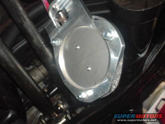 Close-up of a silver throttle body with two bolts, mounted on black tubing
