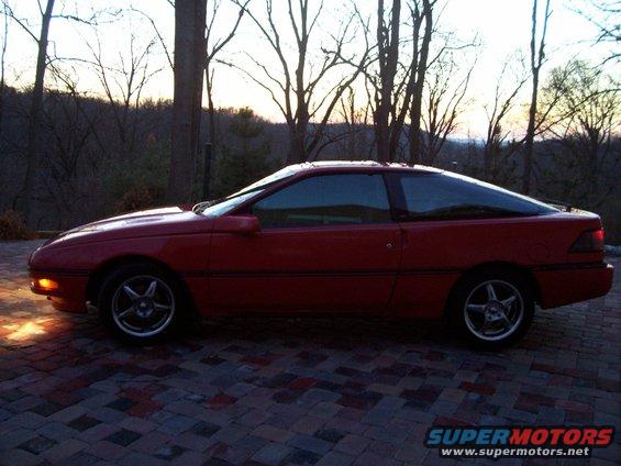 1989 Ford Probe coupe, side view, parked on a brick patio at dusk