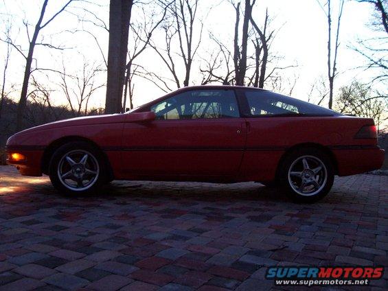 Red 1989 Ford Probe parked on brick pavers, side view