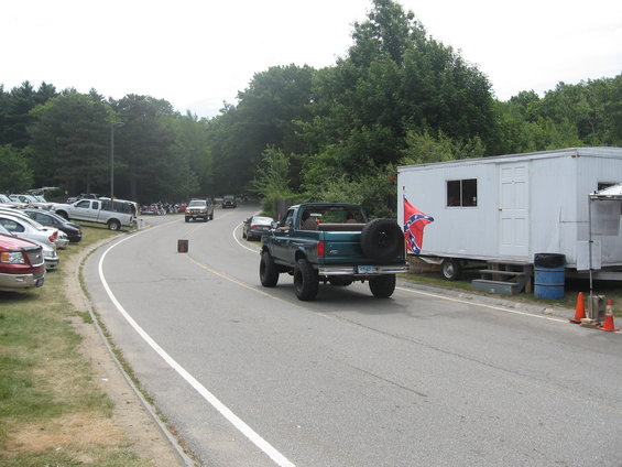 Green lifted pickup truck with spare tire on back, seen from rear