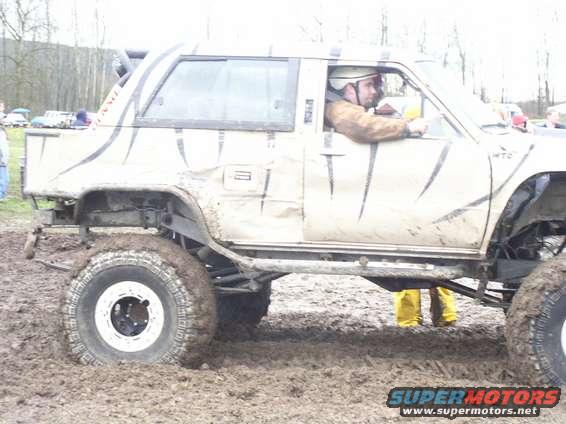 Side view of a mud-splattered off-road vehicle with tiger stripes, stuck in mud