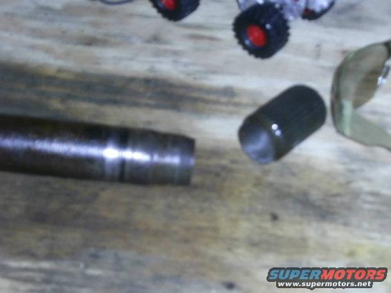 Metal shaft with a collar and a separate cylindrical part on a wooden surface