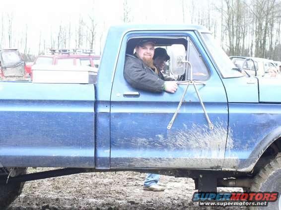 Blue pickup truck side view, mud splattered, two men in cab