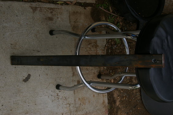 Metal bar resting across chrome stool legs and a black seat