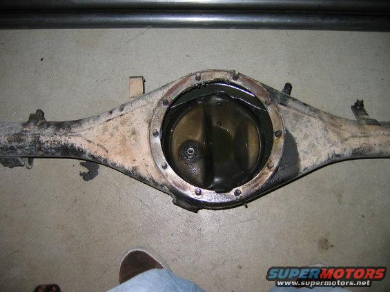 Differential axle housing with open differential cover, showing gears and oil