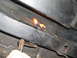 1969 Ford Torino - A bolt on a vehicle's frame rail is heated with a torch, likely during a repair of the rear suspension components.