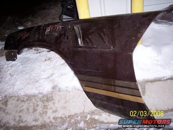 Brown car fender with gold stripes and handwritten numbers, resting on snow