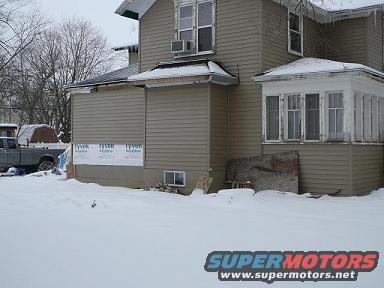House foundation with siding and windows, truck in background
